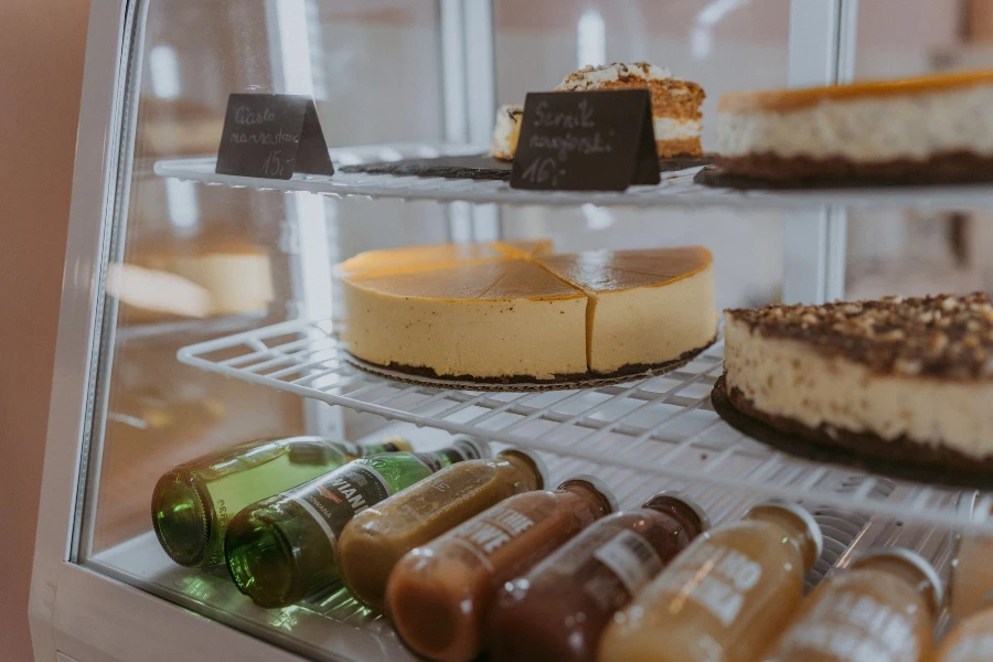 Świeże ciasta i soki w szklanych butelkach w lodówce w kawiarni w Radomiu