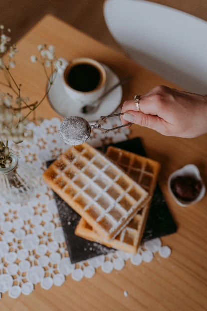 Domowe gofry posypane cukrem pudrem i kawa na stole w kawiarni w Radomiu