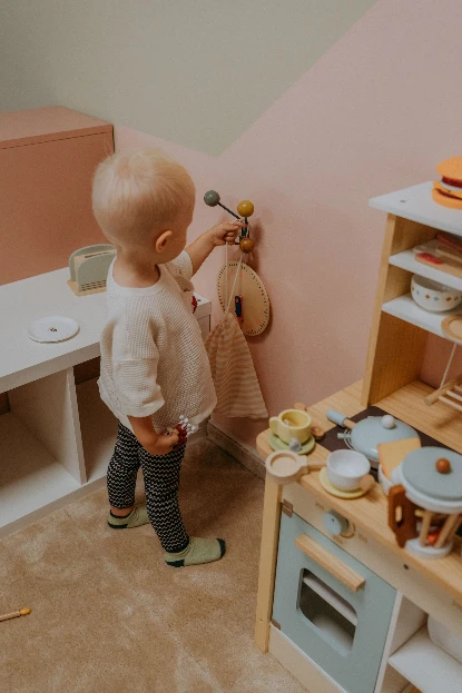 Małe dziecko bawiące się w drewnianą kuchnię w bawialni w Radomiu